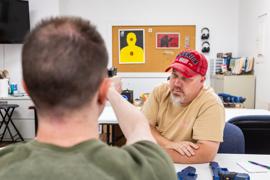 Firearm safety instructor providing supervised instruction at an indoor shooting range