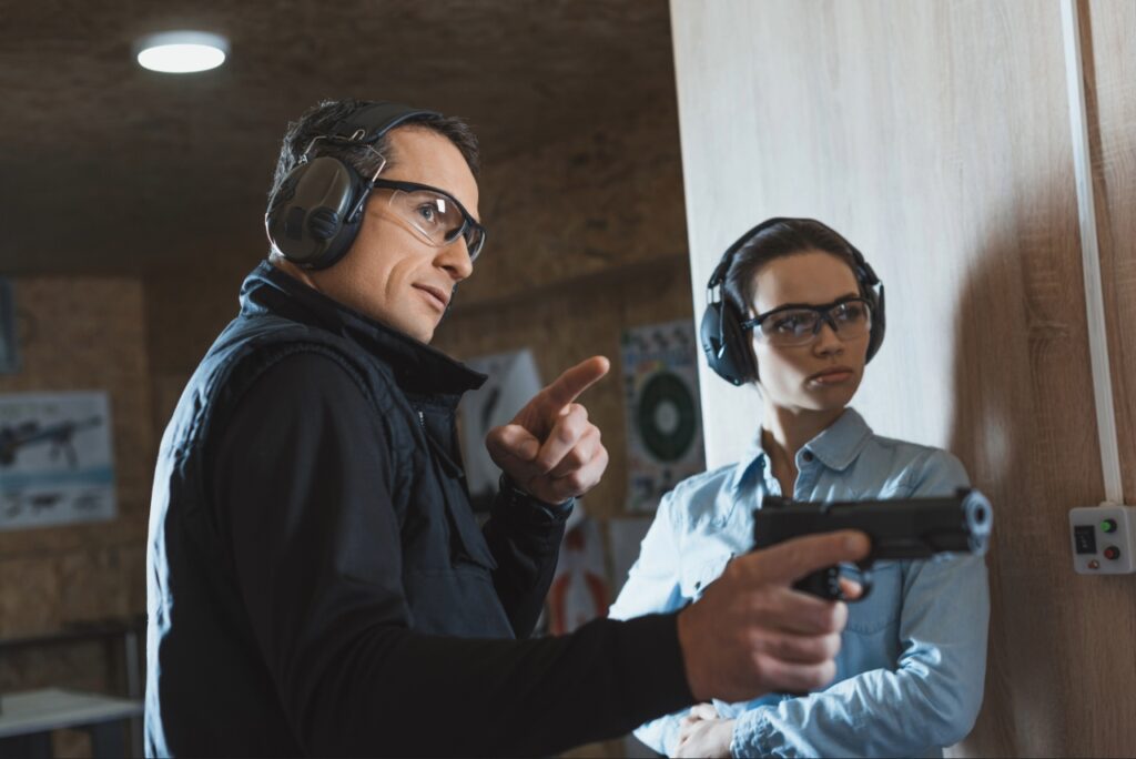 Firearm instructor coaching a student on stance and trigger control at an indoor range