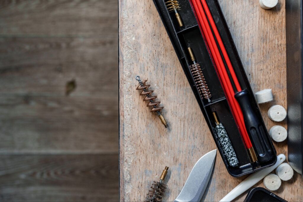 handgun cleaning in Sarasota | Firearm cleaning kit with brushes, solvent, lubricant, patches, and cleaning rod arranged on a workbench